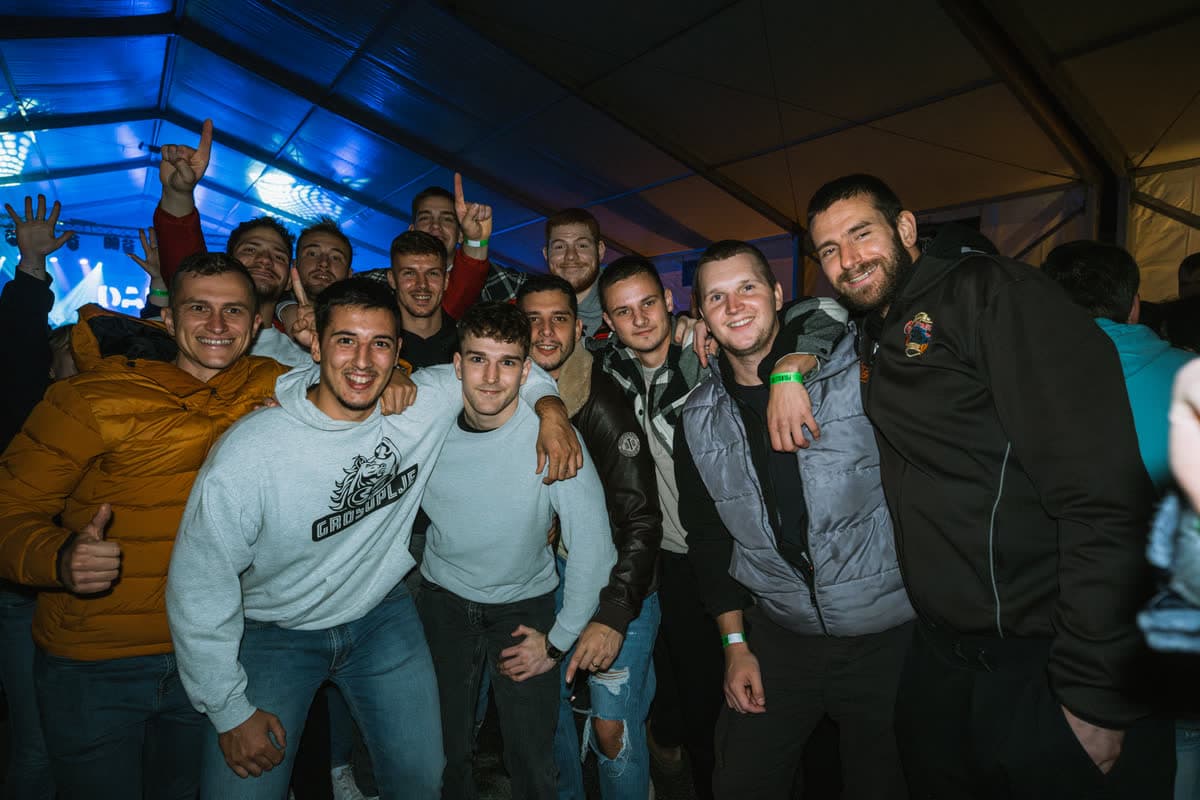 Nasmejana družba obiskovalcev pozira v objektiv pod šotorom leta 2024.